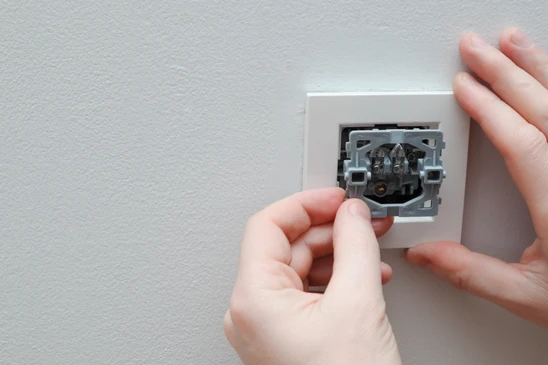 Intérieur résidentiel avec mains d'électricien installant un mécanisme d'interrupteur dans boîtier d'encastrement mural